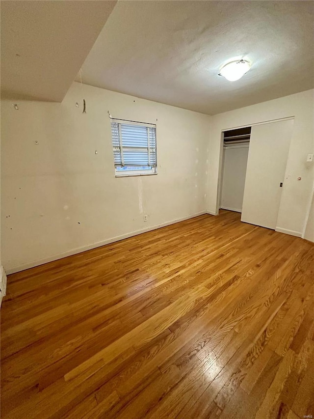 unfurnished bedroom featuring light wood-type flooring, a textured ceiling, and a closet