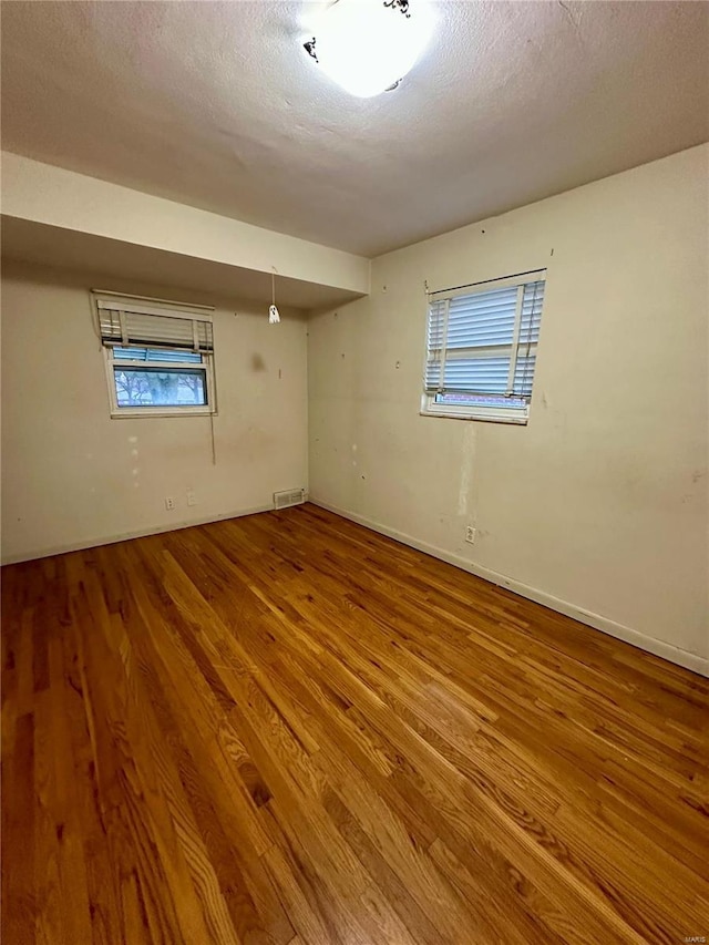 basement featuring hardwood / wood-style flooring and a textured ceiling