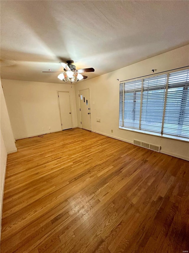 empty room featuring a textured ceiling, light hardwood / wood-style flooring, and ceiling fan