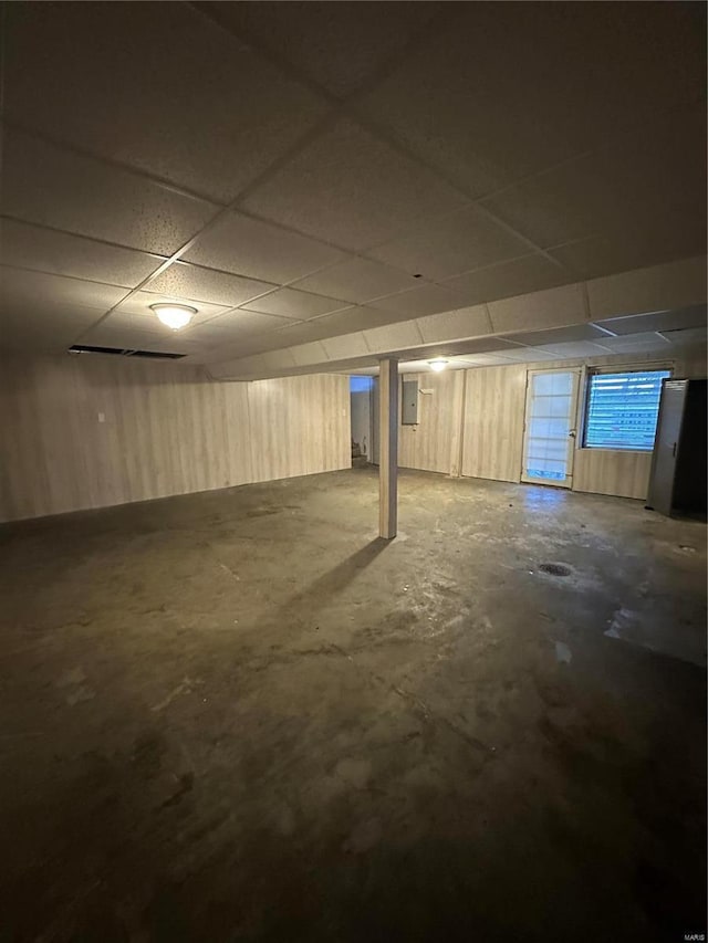 basement featuring a paneled ceiling and electric panel