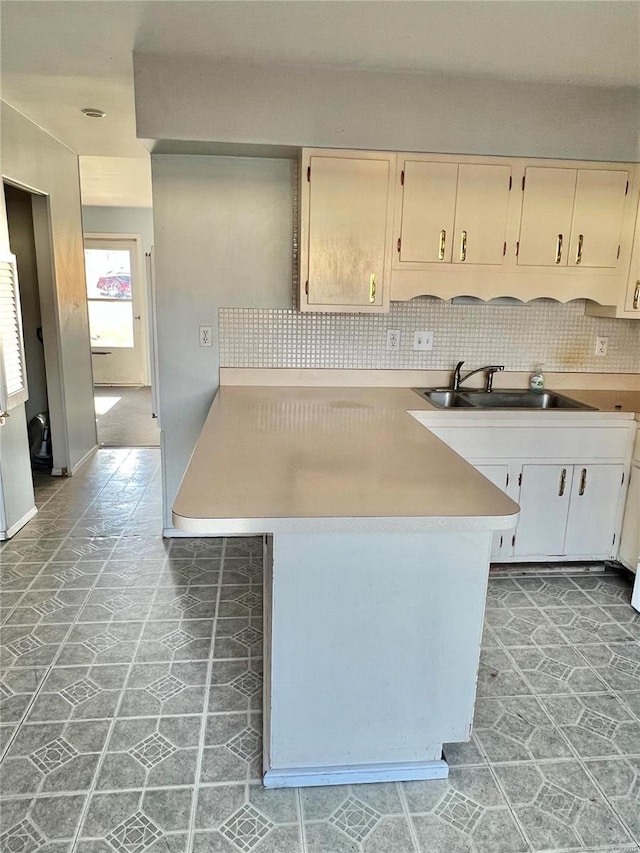 kitchen featuring decorative backsplash, kitchen peninsula, and sink