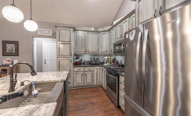 kitchen featuring lofted ceiling, dark wood-type flooring, light stone countertops, appliances with stainless steel finishes, and decorative light fixtures