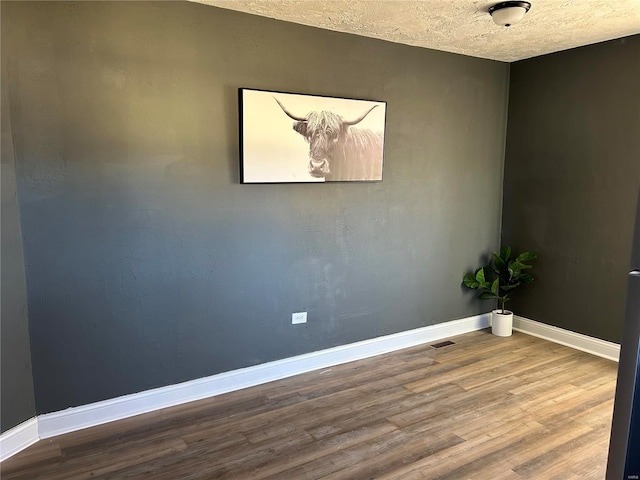 spare room featuring hardwood / wood-style floors and a textured ceiling