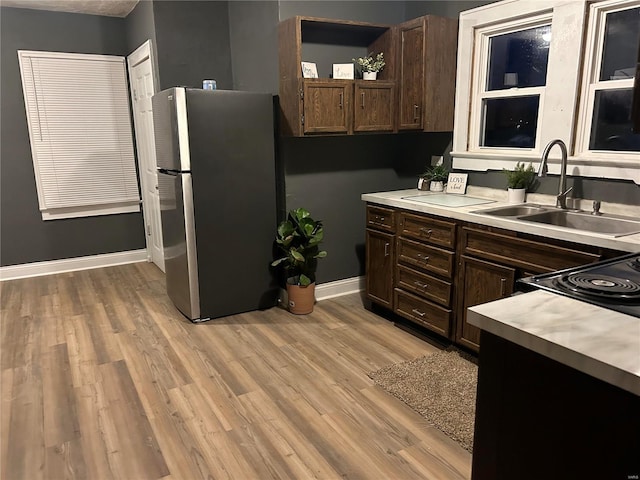 kitchen featuring stainless steel fridge, dark brown cabinetry, light hardwood / wood-style floors, and sink