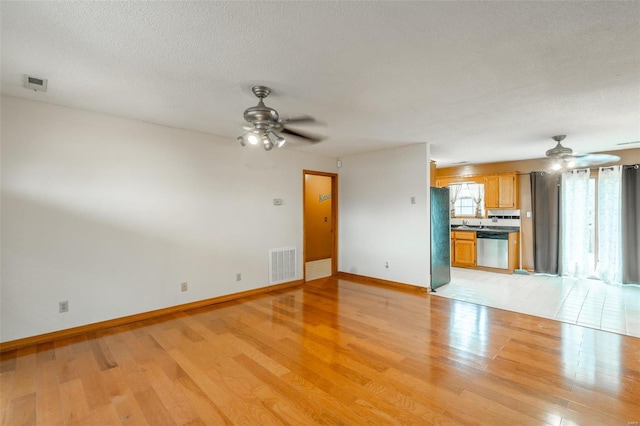 unfurnished living room with a textured ceiling, light wood-type flooring, and ceiling fan