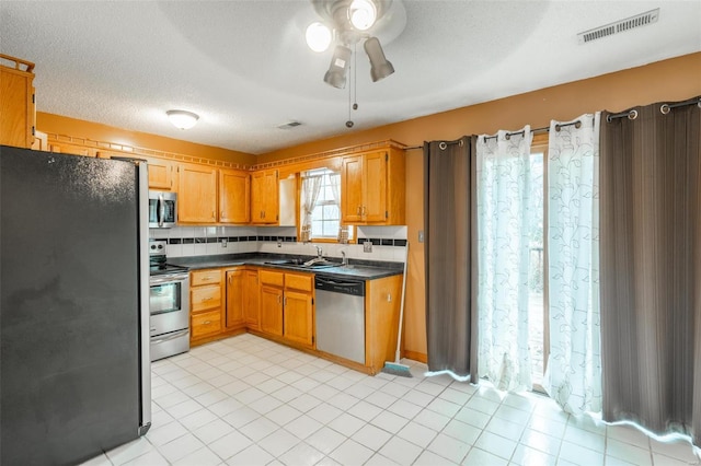 kitchen with sink, ceiling fan, a textured ceiling, tasteful backsplash, and stainless steel appliances