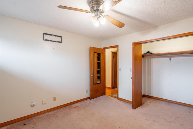 unfurnished bedroom featuring a closet, a textured ceiling, light colored carpet, and ceiling fan