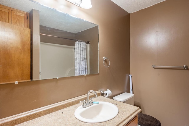 bathroom with a shower with curtain, vanity, a textured ceiling, and toilet