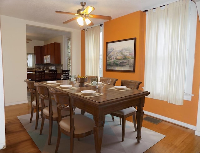 dining room with ceiling fan and light hardwood / wood-style floors