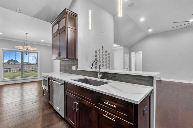 kitchen with sink, stainless steel dishwasher, pendant lighting, vaulted ceiling, and decorative backsplash