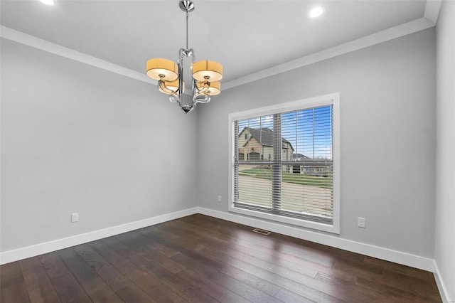 empty room featuring crown molding, dark wood-type flooring, and a notable chandelier