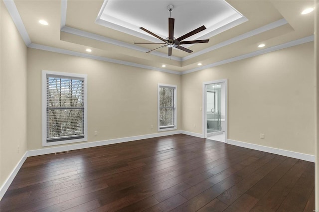 empty room with ceiling fan, dark hardwood / wood-style flooring, crown molding, and a tray ceiling