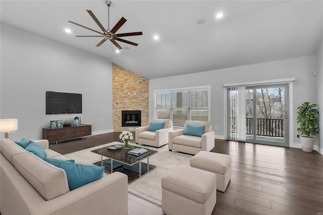 living room with ceiling fan, a stone fireplace, wood-type flooring, and high vaulted ceiling