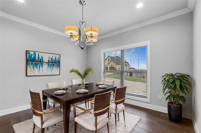 dining area with dark wood-type flooring, a chandelier, and ornamental molding