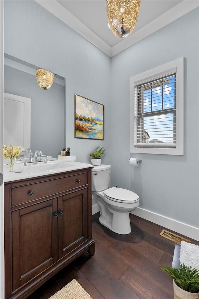 bathroom with wood-type flooring, vanity, toilet, and crown molding