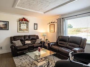 living room with hardwood / wood-style floors, a textured ceiling, a tray ceiling, and crown molding