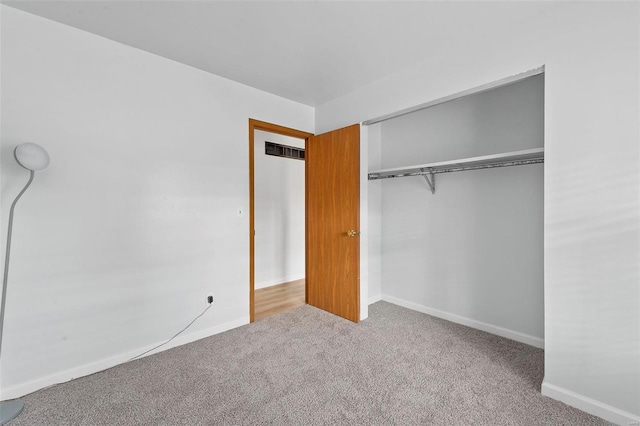 unfurnished bedroom featuring light carpet and a closet