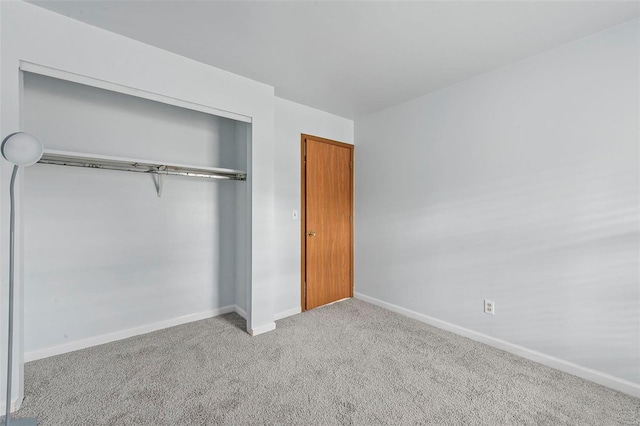 unfurnished bedroom featuring light carpet and a closet