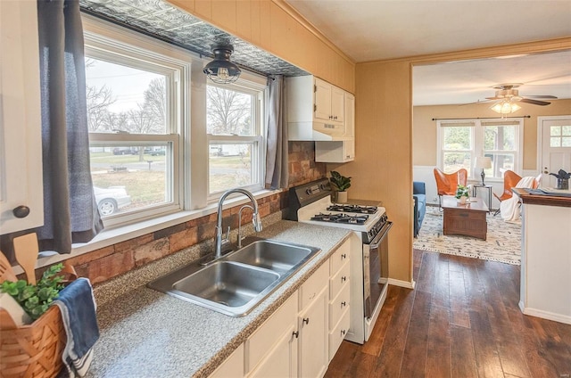 kitchen with white gas range, ceiling fan, dark wood-type flooring, sink, and white cabinets