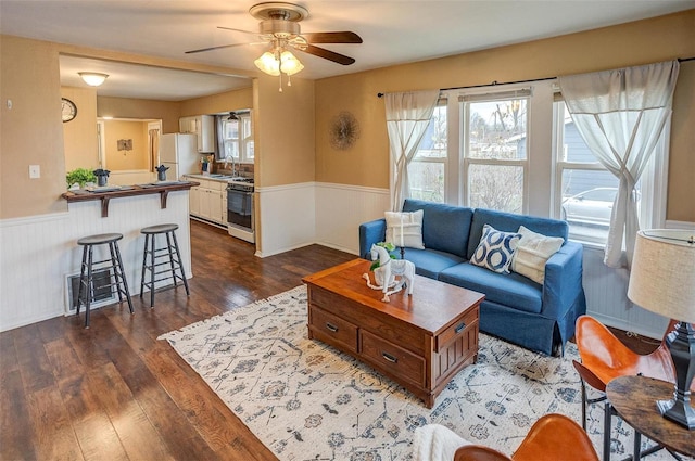 living room with dark hardwood / wood-style floors, ceiling fan, and sink