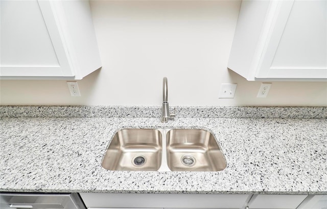 details with light stone countertops, sink, and white cabinets