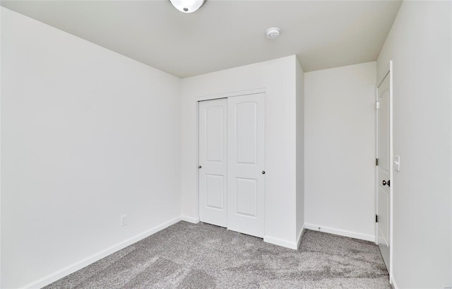 unfurnished bedroom featuring light colored carpet and a closet