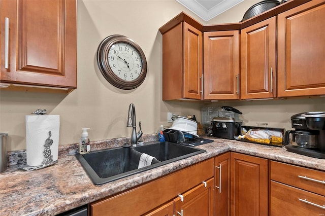 kitchen with light stone counters, crown molding, and sink