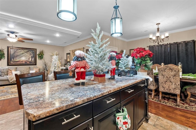 kitchen featuring light stone counters, ceiling fan with notable chandelier, crown molding, light hardwood / wood-style flooring, and a kitchen island