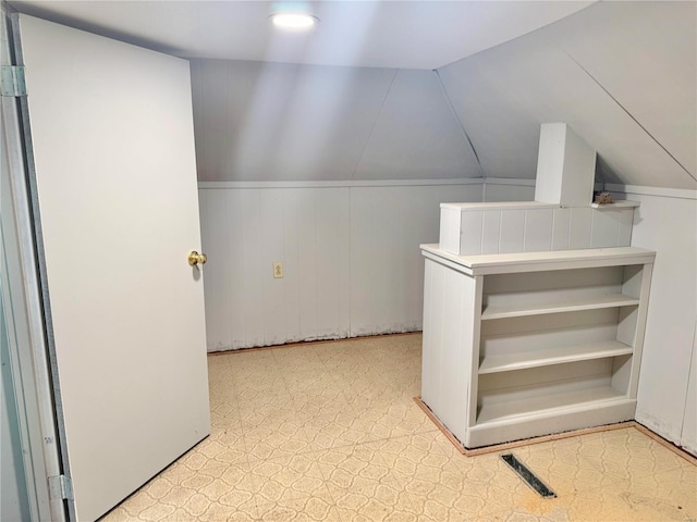 bonus room with visible vents, light floors, wooden walls, and vaulted ceiling