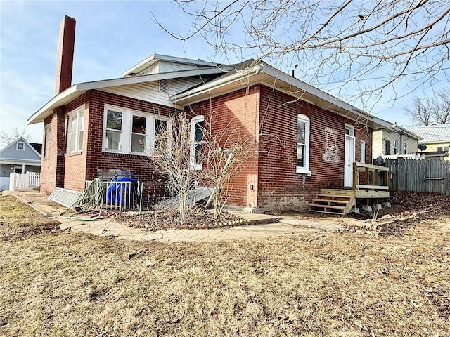 exterior space featuring fence, brick siding, and a chimney