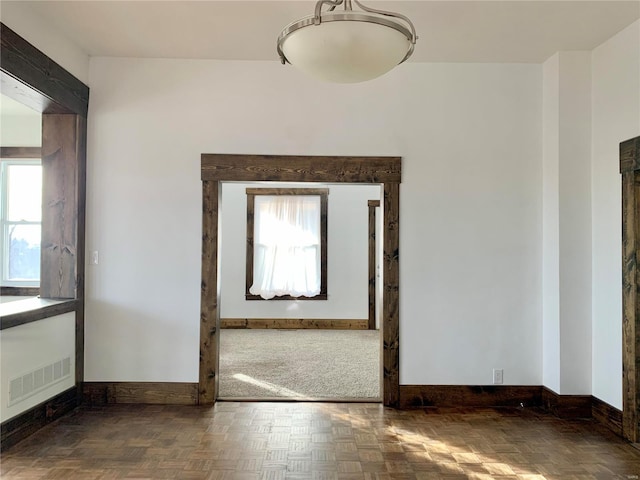 unfurnished room with a wealth of natural light, visible vents, and baseboards