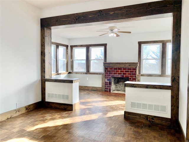 unfurnished living room featuring visible vents, baseboards, a brick fireplace, and ceiling fan