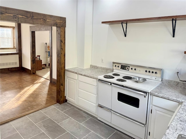 kitchen with white cabinetry, light countertops, electric range, and visible vents