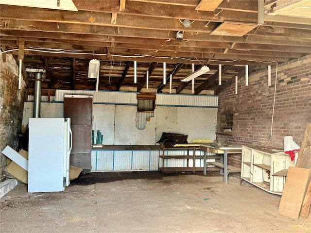 interior space featuring brick wall and freestanding refrigerator