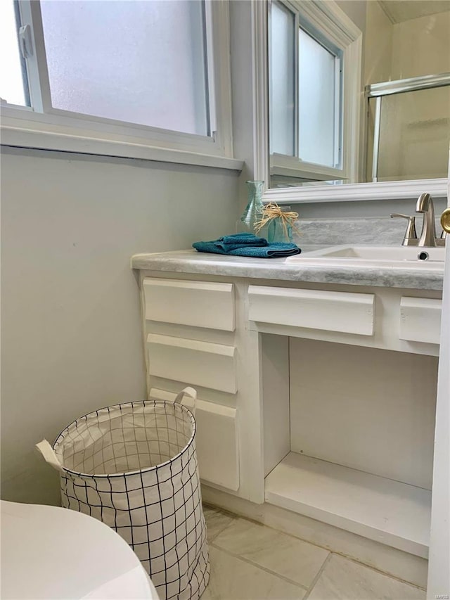 bathroom with vanity, toilet, a healthy amount of sunlight, and a shower with door