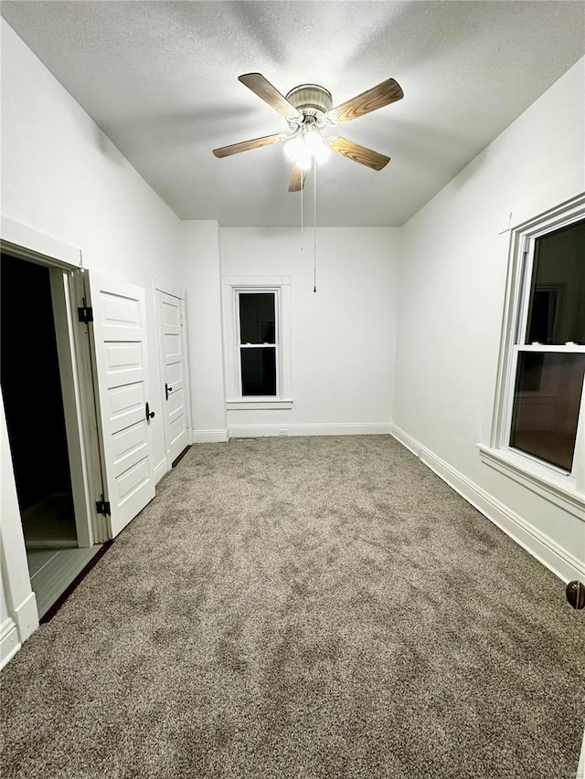 carpeted spare room featuring baseboards, a textured ceiling, and ceiling fan