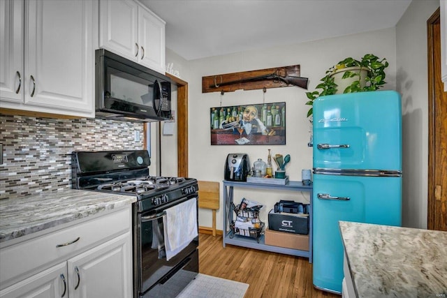 kitchen featuring light stone countertops, light wood-type flooring, backsplash, black appliances, and white cabinetry