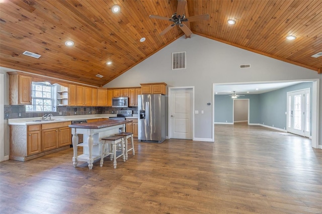 kitchen with a center island, stainless steel appliances, high vaulted ceiling, and light hardwood / wood-style flooring