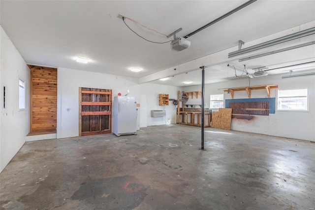 garage featuring white refrigerator, wooden walls, a garage door opener, and an AC wall unit