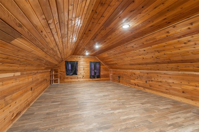 additional living space with wood walls, light hardwood / wood-style floors, lofted ceiling, and wooden ceiling