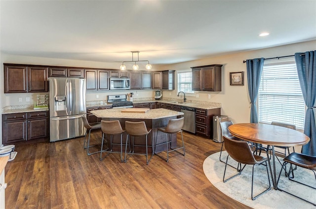 kitchen featuring a center island, hanging light fixtures, sink, appliances with stainless steel finishes, and dark brown cabinetry