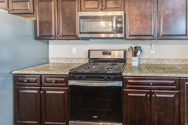 kitchen featuring light stone countertops, dark brown cabinetry, and appliances with stainless steel finishes