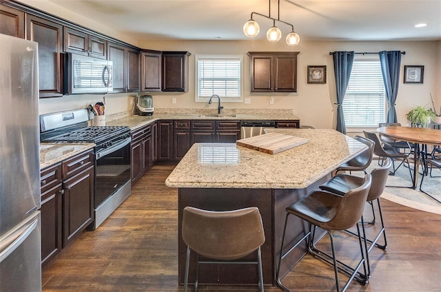 kitchen with sink, hanging light fixtures, dark hardwood / wood-style flooring, a kitchen island, and appliances with stainless steel finishes