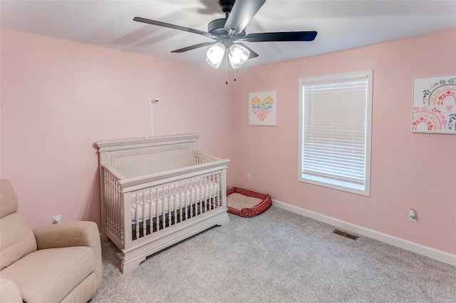 bedroom featuring carpet, a nursery area, and ceiling fan