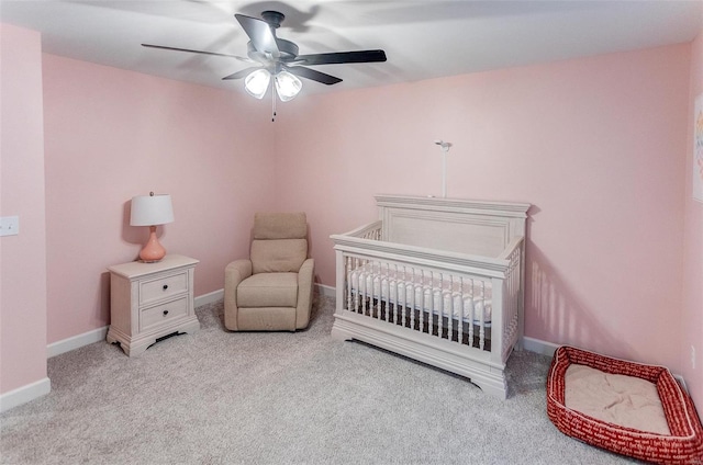 carpeted bedroom featuring ceiling fan and a nursery area