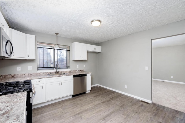 kitchen featuring pendant lighting, stainless steel appliances, white cabinetry, and sink