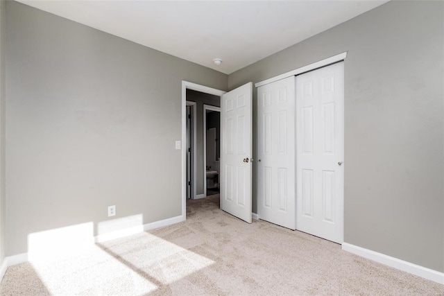 unfurnished bedroom with a closet and light colored carpet