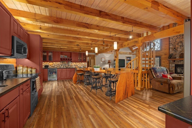 kitchen featuring black electric range oven, a fireplace, beam ceiling, wood-type flooring, and beverage cooler