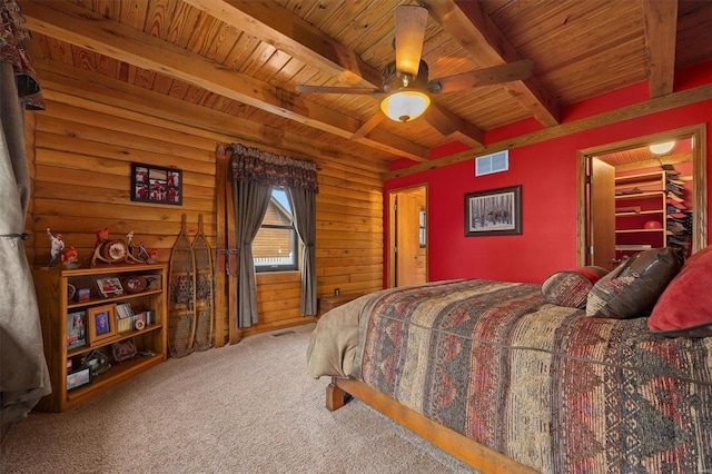 carpeted bedroom featuring beam ceiling, a walk in closet, ceiling fan, and wood ceiling