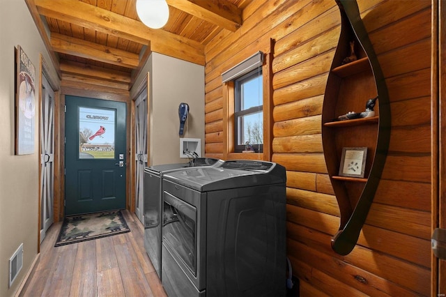 washroom with washing machine and clothes dryer, wooden ceiling, log walls, and dark wood-type flooring